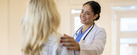 Close up of a nurse practitioner smiling while speaking with a patient during a consultation.