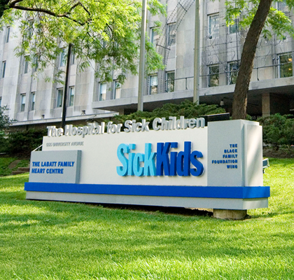 SickKids Hospital sign in front of the main building with trees in the background.