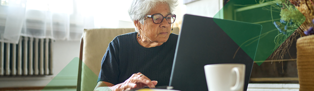 An older woman using a laptop at home.