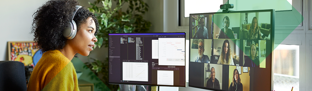 A person wearing headphones attending a video meeting at a home office desk.