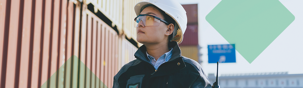 A worker wearing a hard hat and safety glasses at an industrial site.