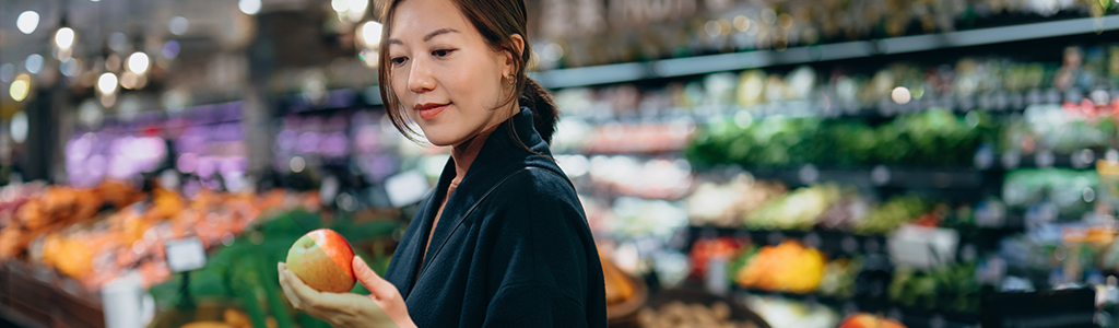 A woman choosing fruit in a grocery store.