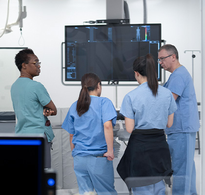 Medical staff discussing imaging results in a hospital procedure room.