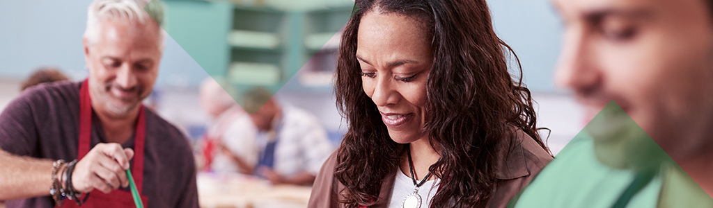 People cooking together and smiling in a community kitchen.